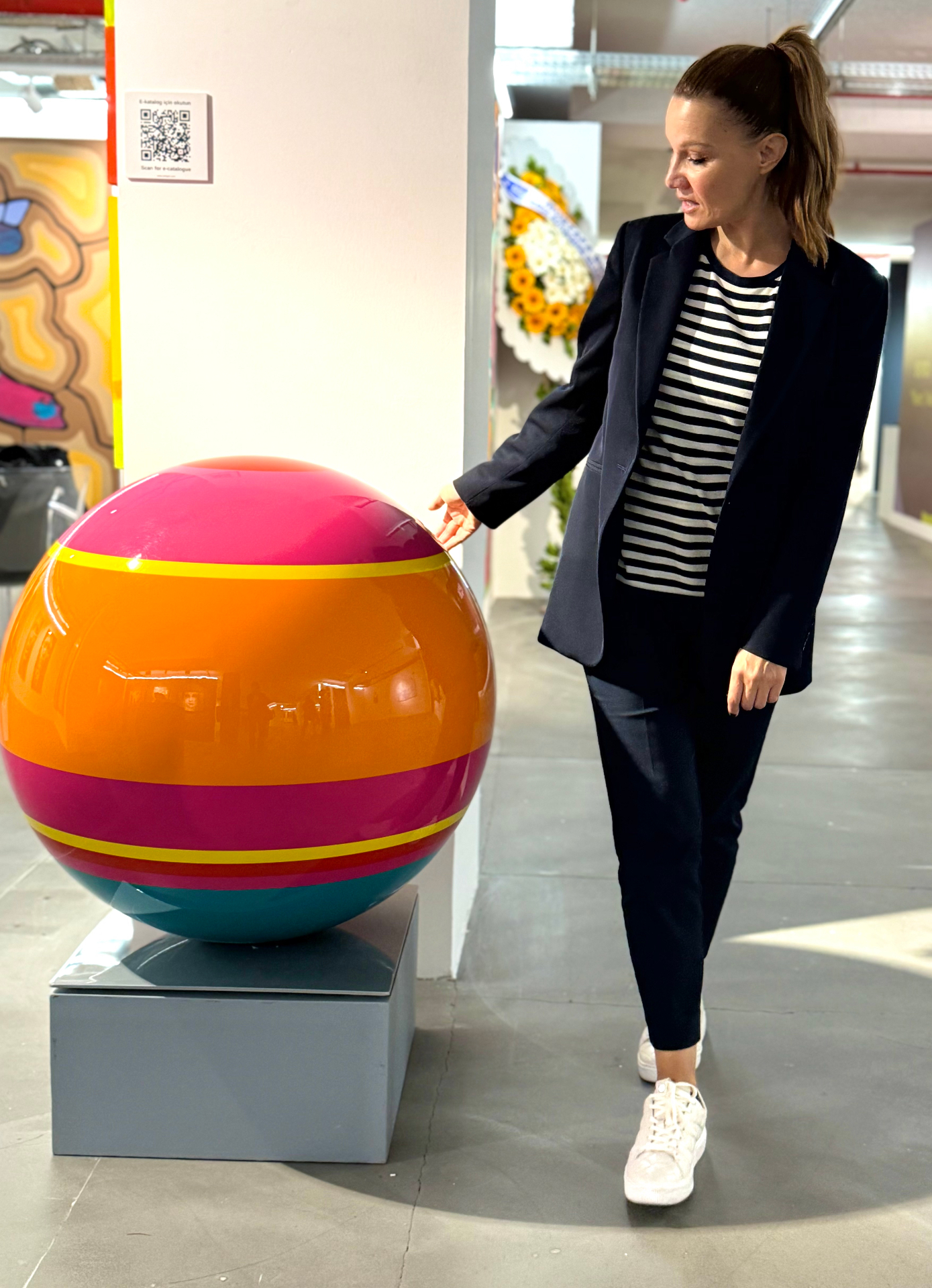 Stiliana Alexieva standing beside the finished striped sphere sculpture on display