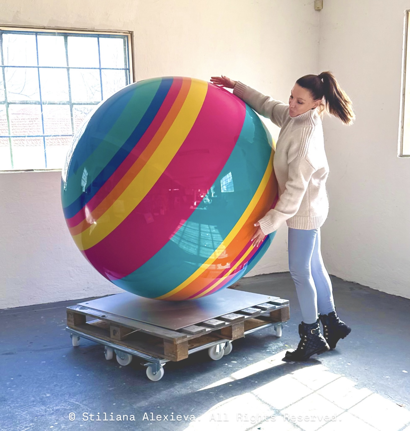 Stiliana Alexieva beside the finished high-gloss striped sphere sculpture in the studio