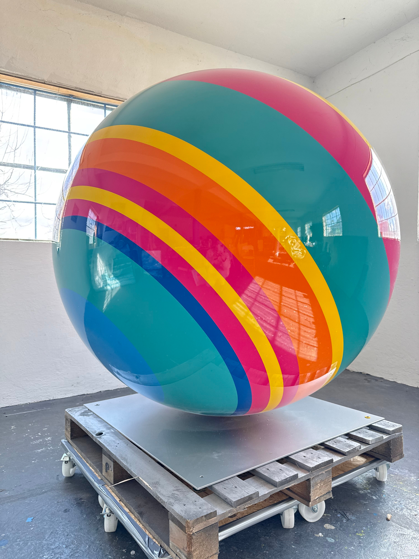 A colourful glossy sphere sculpture in a public plaza